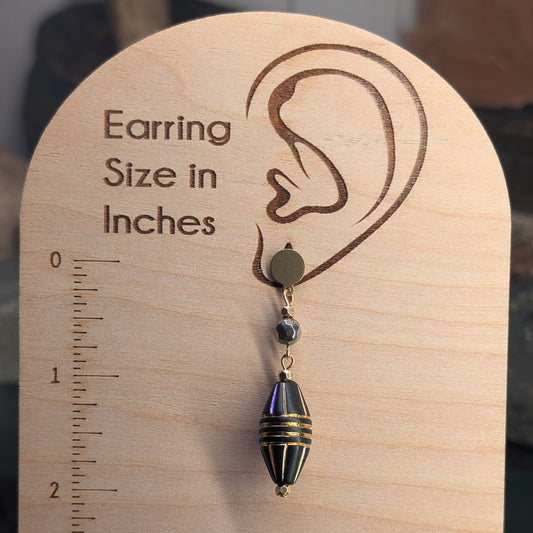 Earring on a wooden size chart with measurements in inches